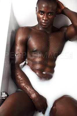 Buy stock photo Shot of a muscular young man having a milky bath at home