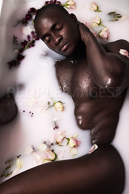 Buy stock photo Shot of a muscular young man having a milky bath filled with flowers at home