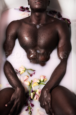 Buy stock photo Cropped shot of a muscular young man having a milky bath filled with flowers at home