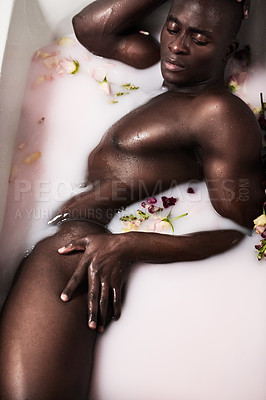 Buy stock photo Shot of a muscular young man having a milky bath filled with flowers at home