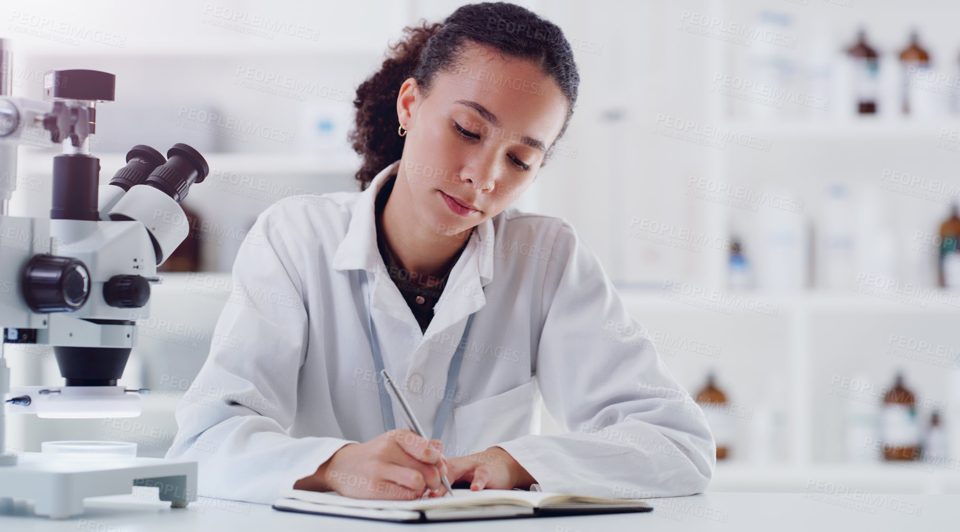 Buy stock photo Shot of a young scientist writing notes while working in a lab