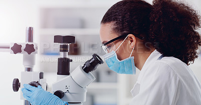 Buy stock photo Shot of a young scientist using a microscope in a lab