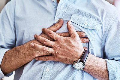 Buy stock photo Cropped shot of an unrecognizable man holding his chest while suffering with heartburn at home