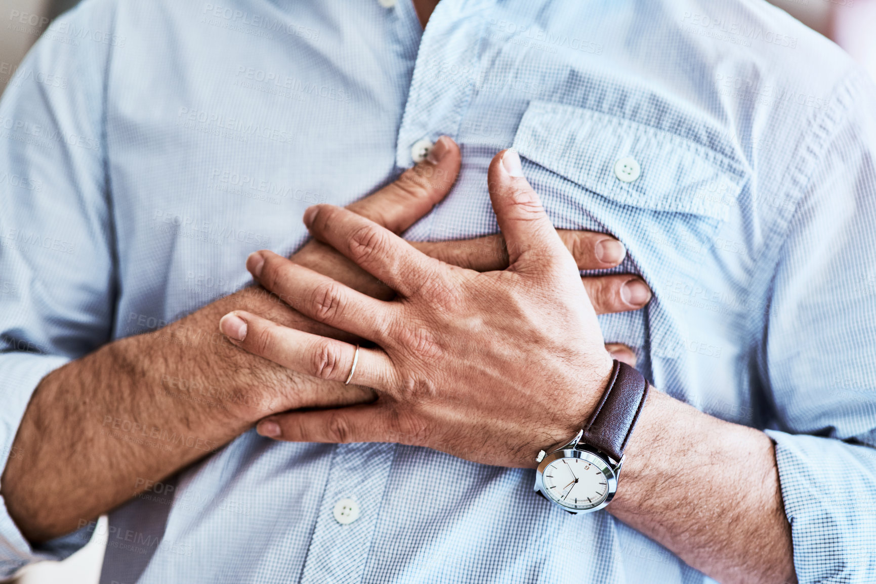Buy stock photo Cropped shot of an unrecognizable man holding his chest while suffering with heartburn at home