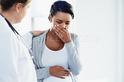 Buy stock photo Cropped shot of a young female doctor trying to comfort a distressed pregnant patient at a hospital during the day