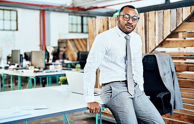 Buy stock photo Cropped portrait of a handsome young businessman sitting on his desk in the office alone