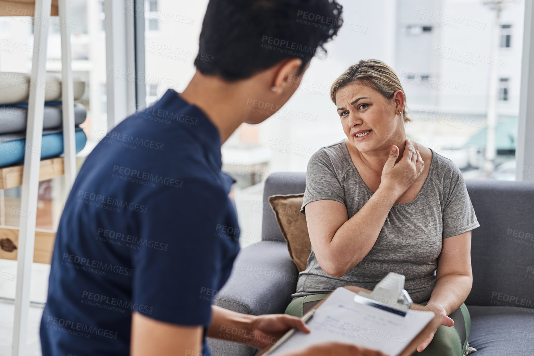 Buy stock photo Shot of a young physiotherapist consulting with a mature woman inside her office at a clinic