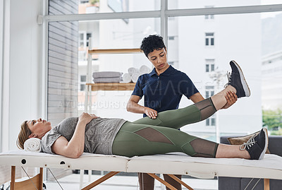 Buy stock photo Shot of a young physiotherapist doing leg exercises with her patient inside her office at a clinic