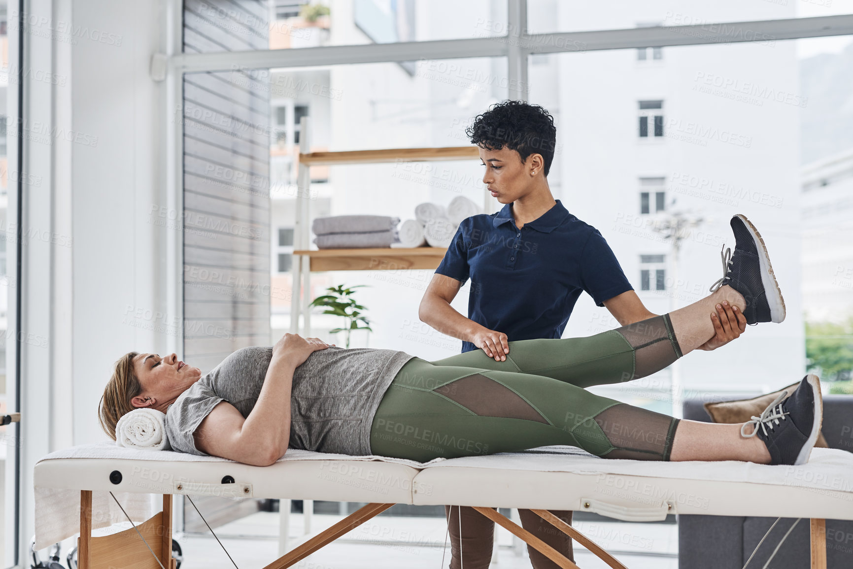 Buy stock photo Shot of a young physiotherapist doing leg exercises with her patient inside her office at a clinic