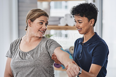 Buy stock photo Shot of a young physiotherapist putting kinesiology tape on a patient's arm at a rehabilitation centre