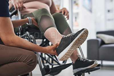 Buy stock photo Cropped shot of an unrecognizable physiotherapist doing leg exercises with her wheelchair bound patient inside her office at a clinic