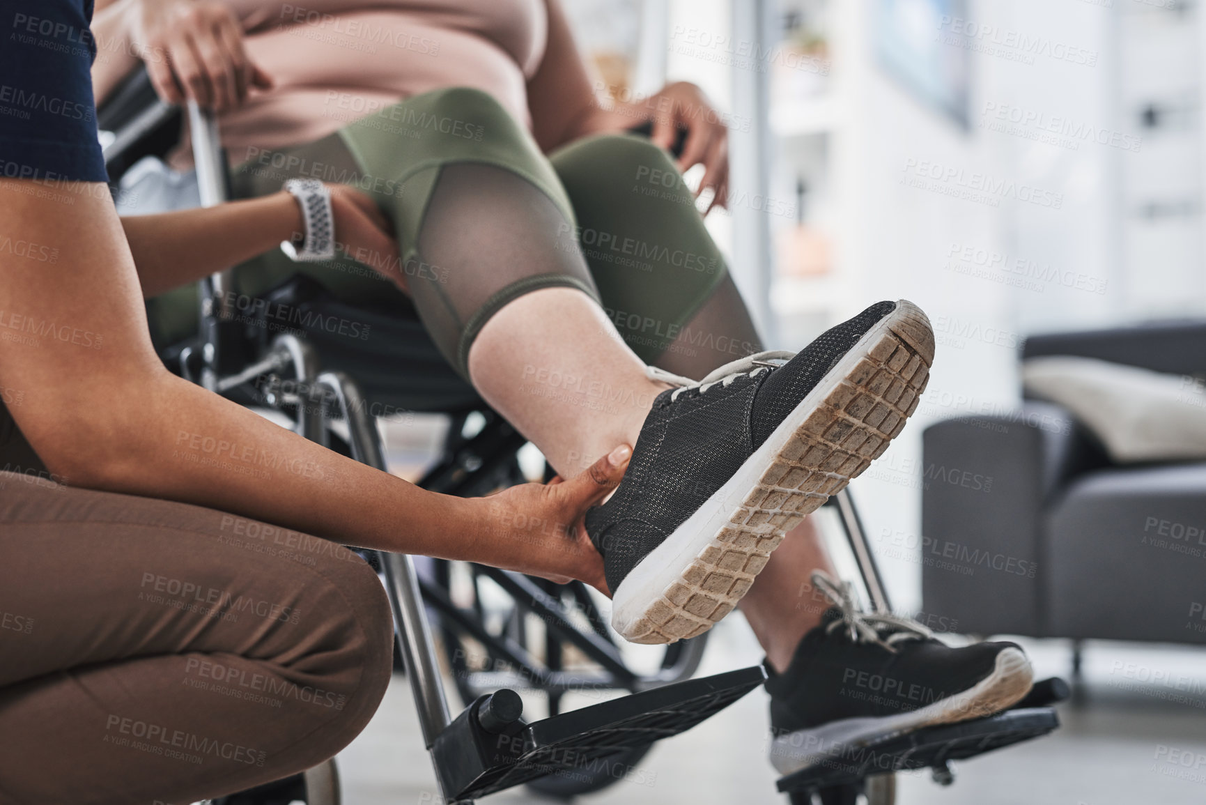 Buy stock photo Cropped shot of an unrecognizable physiotherapist doing leg exercises with her wheelchair bound patient inside her office at a clinic