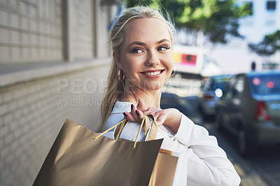 Buy stock photo Cropped shot of an attractive young woman looking away thoughtfully while holding shopping bags in the city during the day