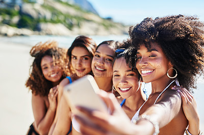 Buy stock photo Shot of a group of happy young women taking selfies together at the beach