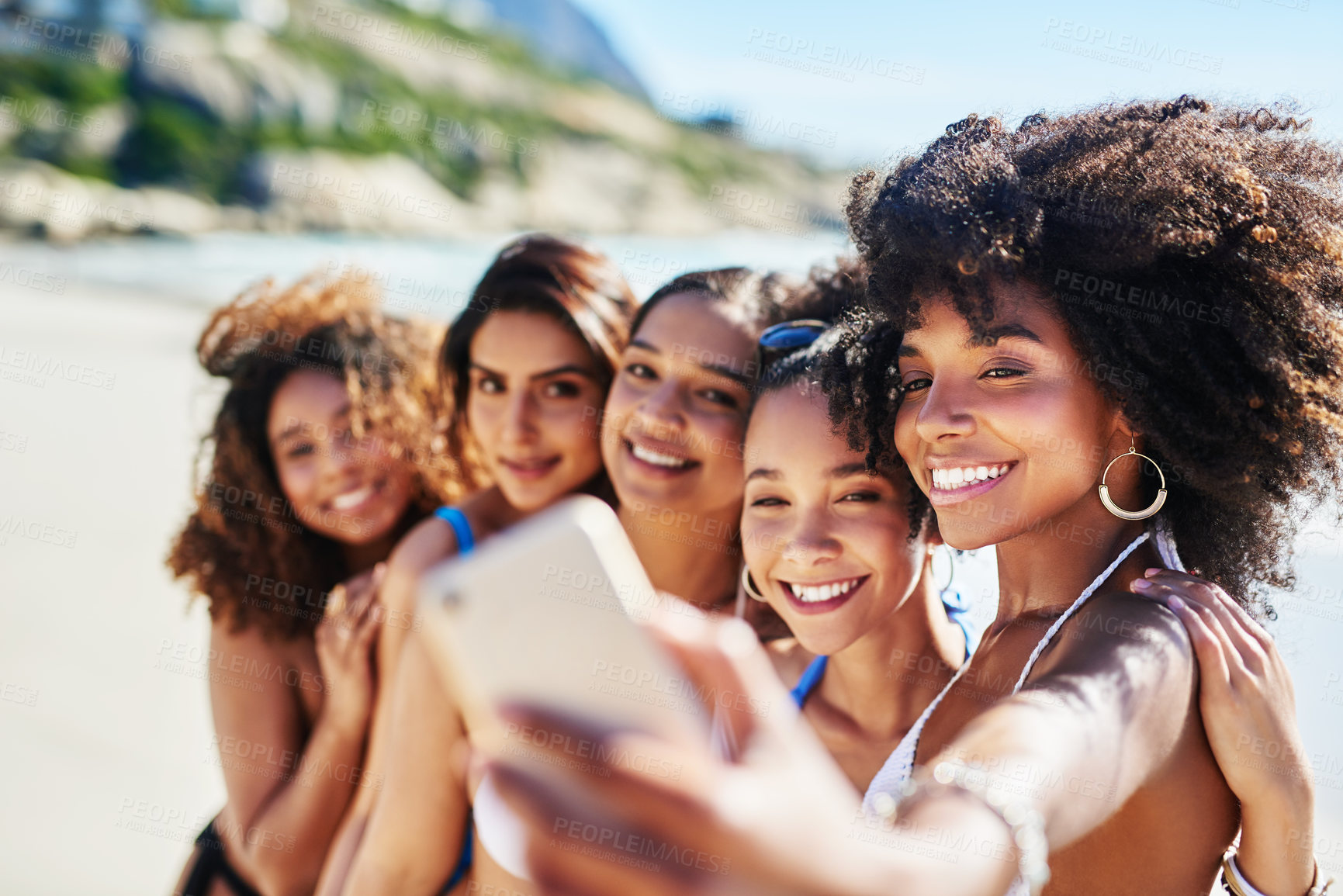 Buy stock photo Shot of a group of happy young women taking selfies together at the beach