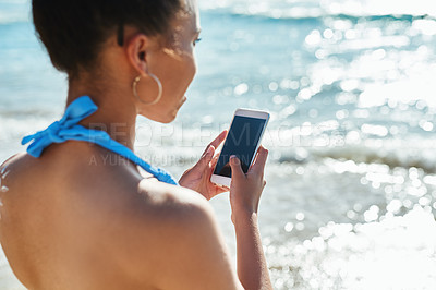 Buy stock photo Shot of a beautiful young woman using a mobile phone at the beach