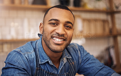 Buy stock photo Cropped shot a handsome young businessman standing alone in his cafe and smiling during the day