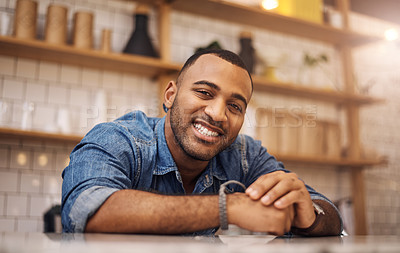 Buy stock photo Cropped shot of a handsome young businessman leaning on the counter in his cafe with his hands clasped