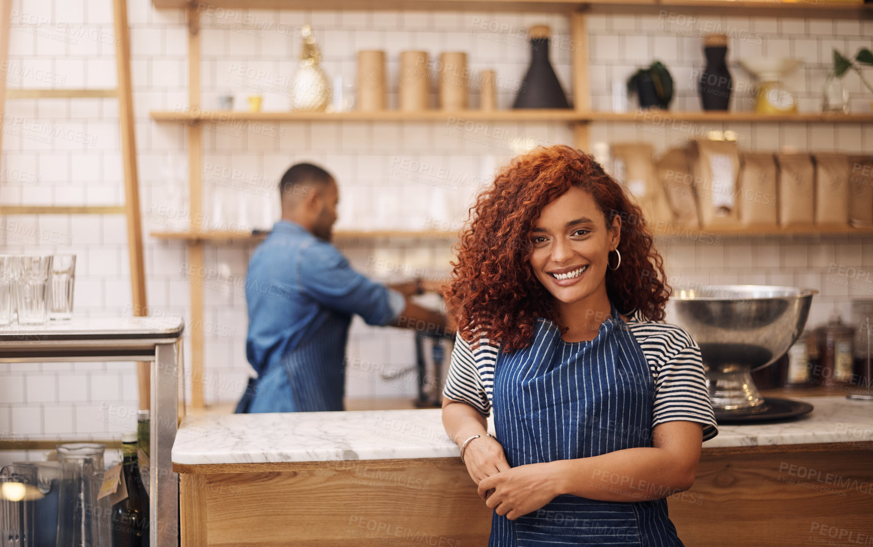 Buy stock photo Cropped shot of an attractive young businesswoman standing in her cafe while a barista works behind her