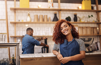 Buy stock photo Cropped shot of an attractive young businesswoman standing in her cafe while a barista works behind her