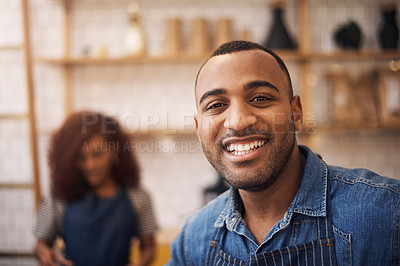 Buy stock photo Cropped shot of a handsome young businessman standing in his cafe while a barista works behind him