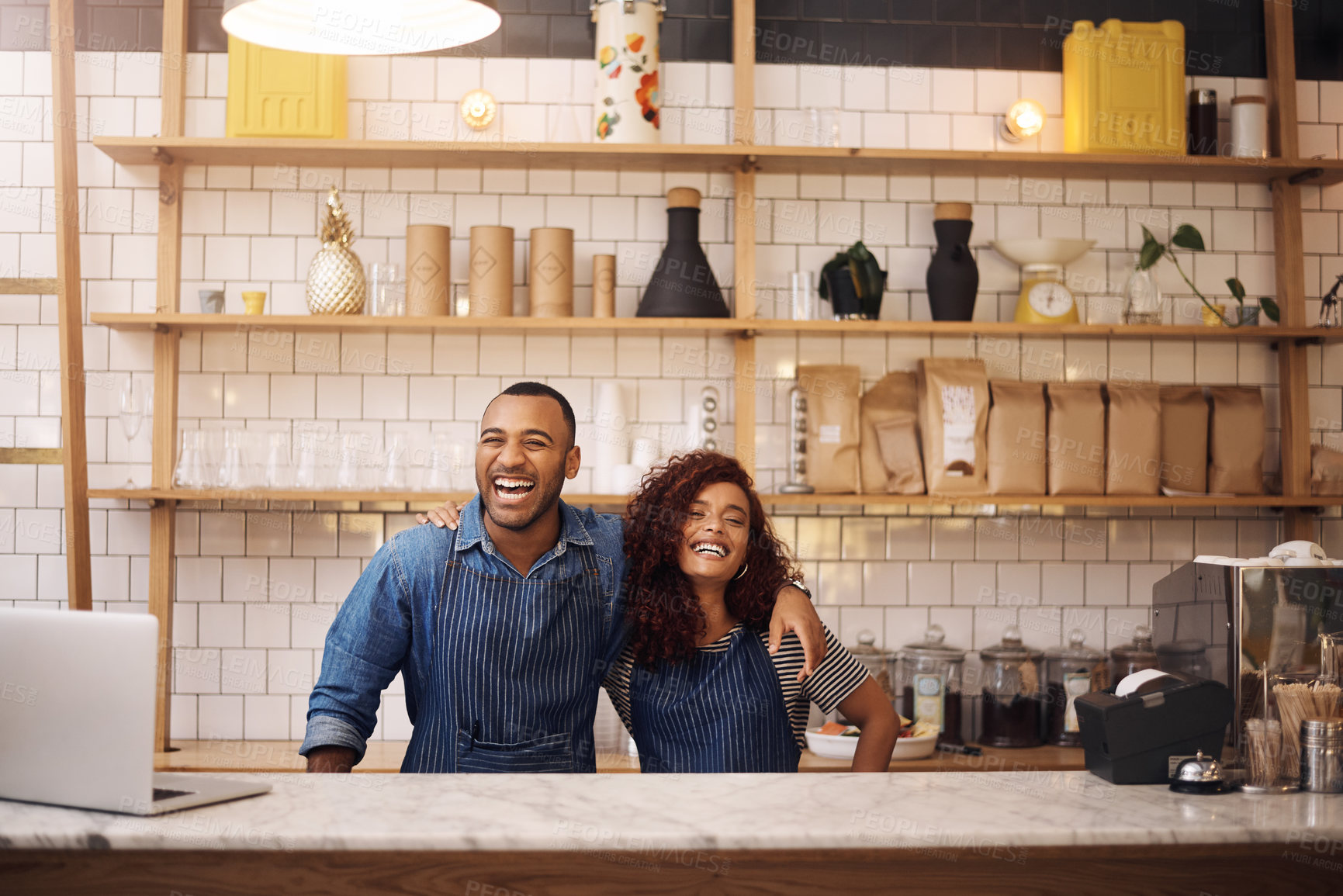 Buy stock photo Cropped shot of two young business owners standing in their cafe with their arms around each other
