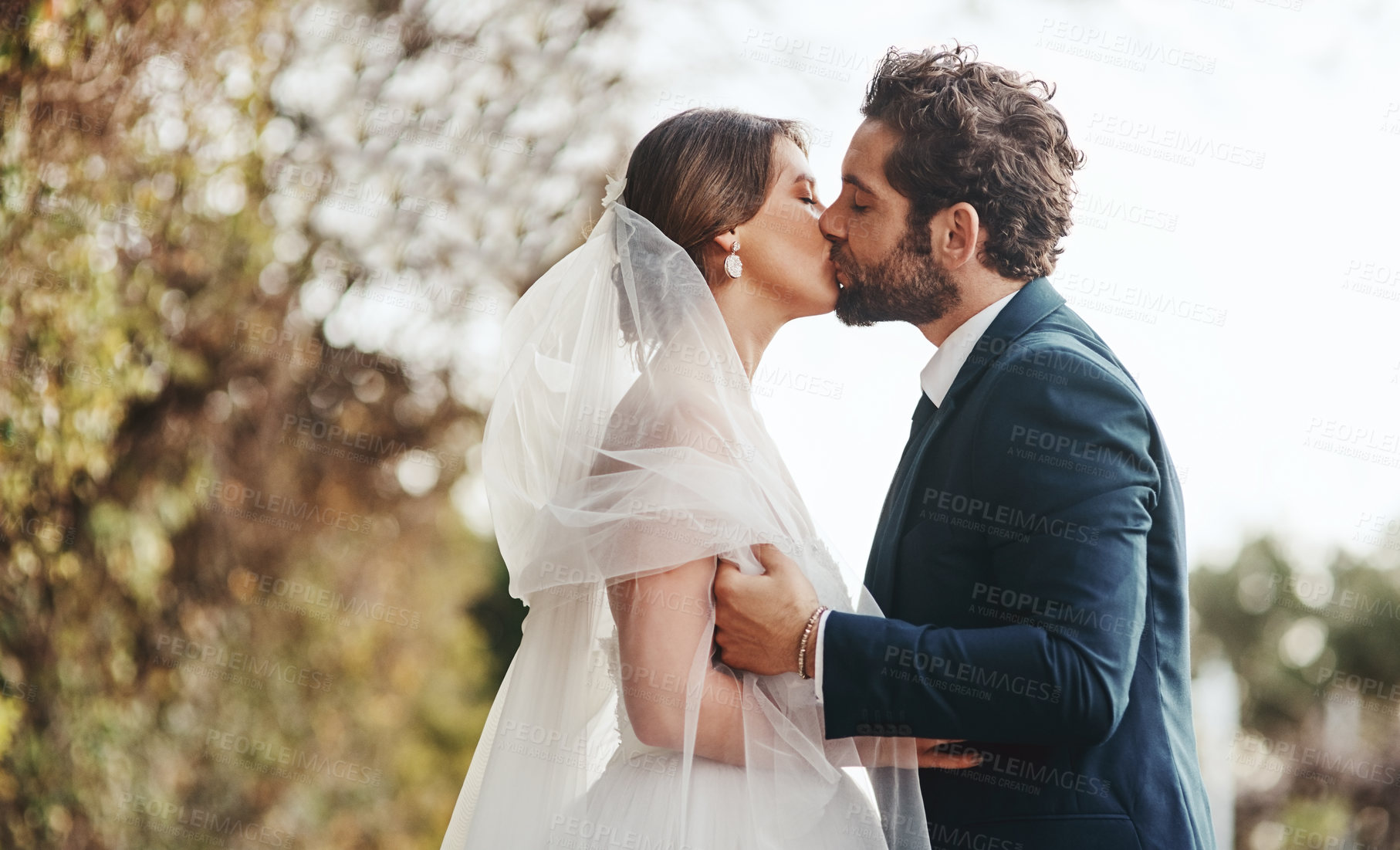 Buy stock photo Marriage, wedding and couple in garden kiss for love, ceremony celebration and commitment in park. Romantic event, trust and bride and groom intimate, embrace and happy for romance, loving and peace