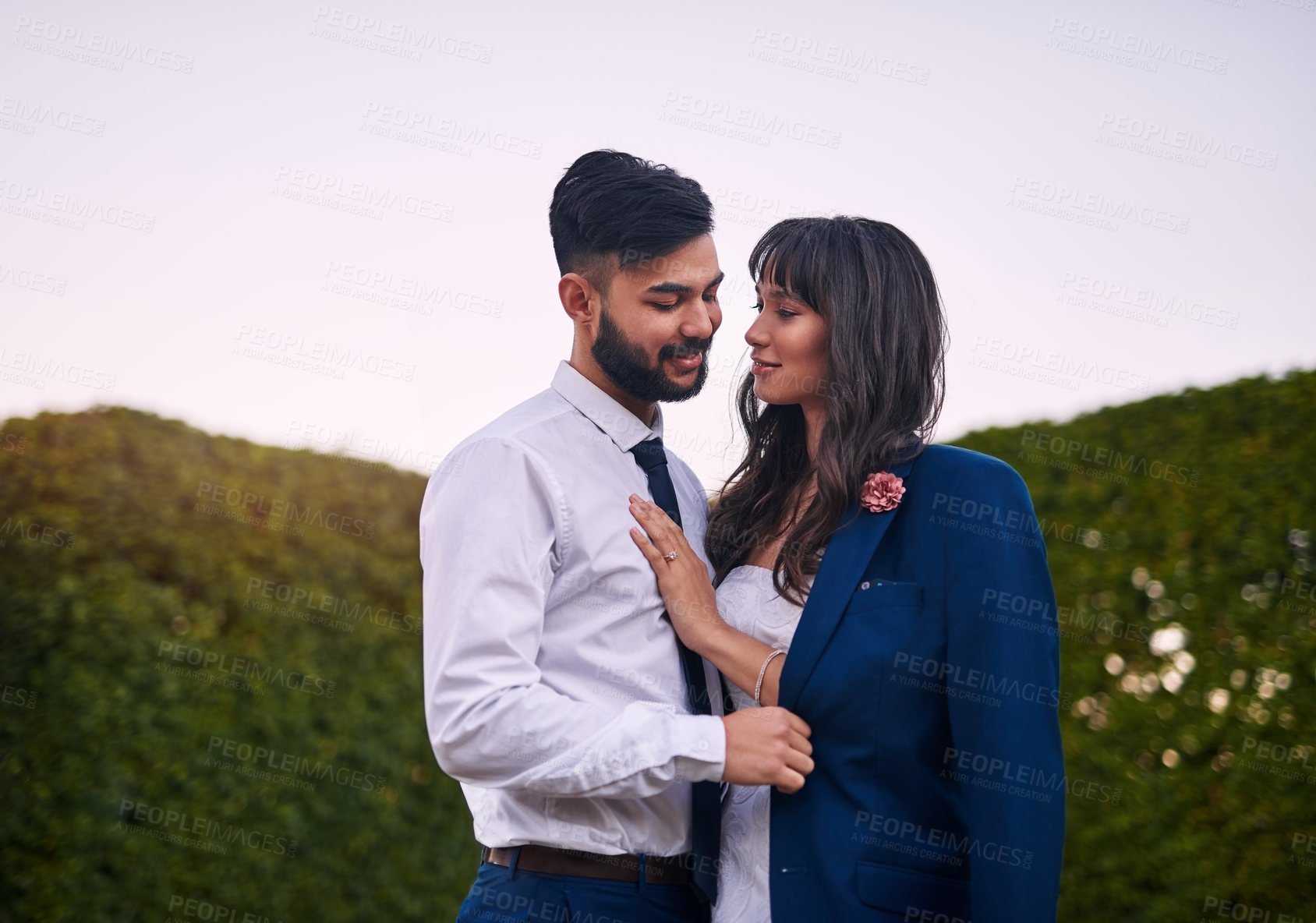 Buy stock photo Cropped shot of an affectionate young bride smiling at her groom while wearing his jacket on their wedding day