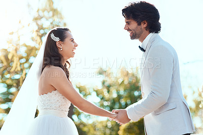 Buy stock photo Cropped shot of an affectionate young newlywed couple smiling at each other while holding hands on their wedding day