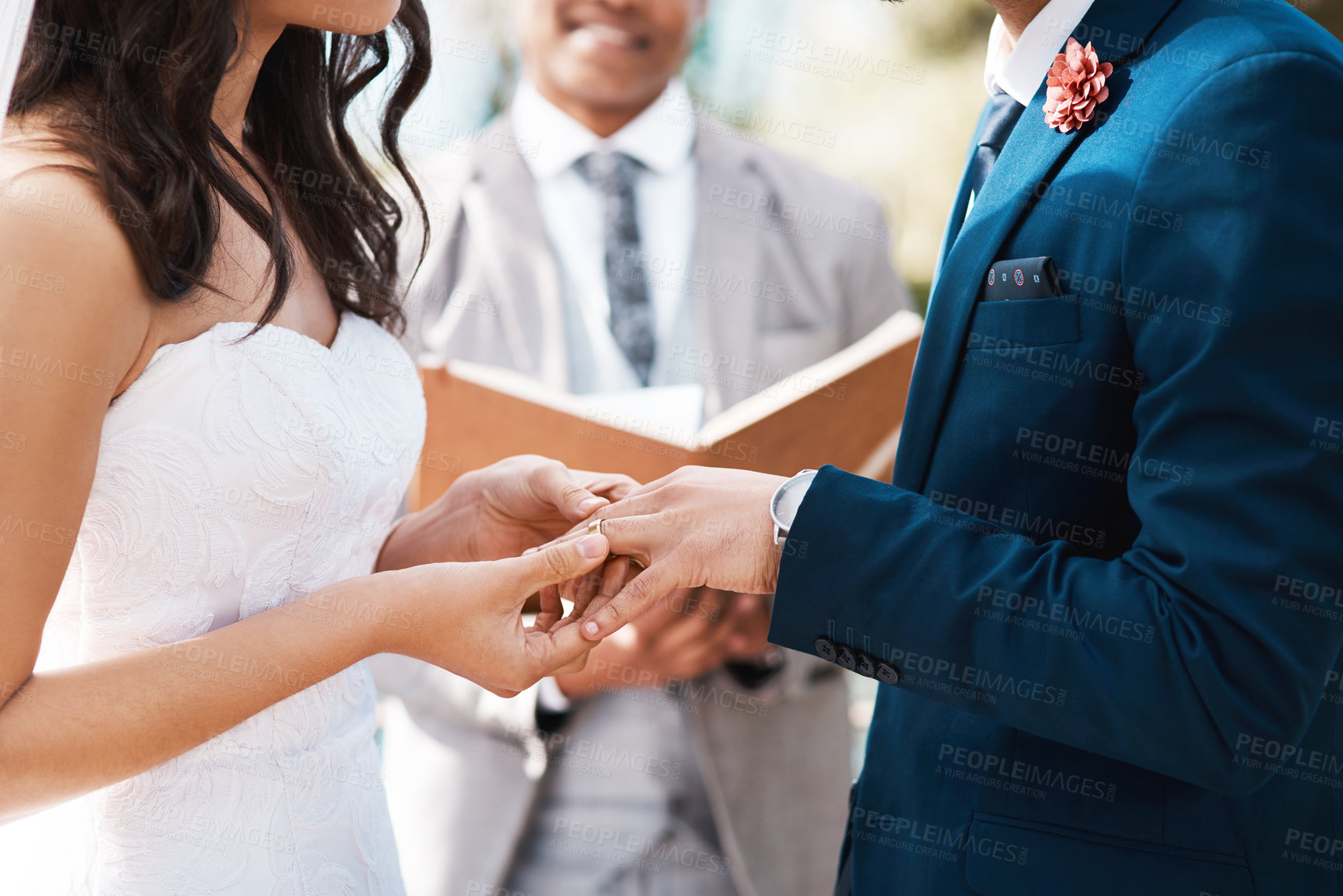 Buy stock photo Cropped shot of an unrecognizable bride slipping a ring on to her groom's finger while standing at the altar on their wedding day