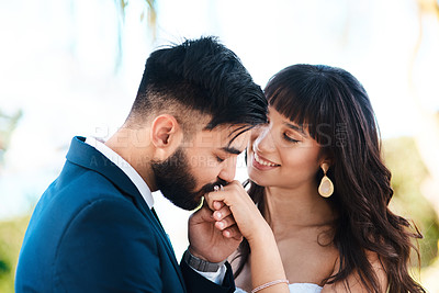 Buy stock photo Cropped shot of an affectionate young bridegroom kissing his bride's hand while standing outdoors on their wedding day