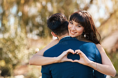 Buy stock photo Cropped shot of an affectionate young bride smiling while making a heart shape on her groom's back on their wedding day