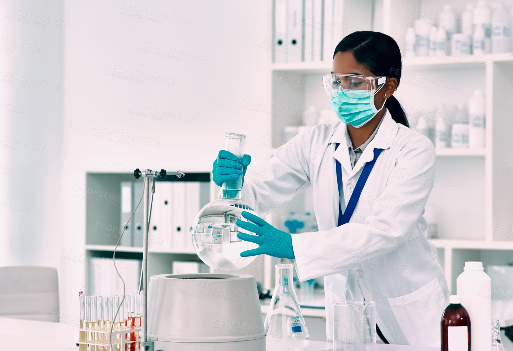 Buy stock photo Cropped shot of an attractive young female scientist placing a florence flask with a liquid into a centrifuge while working in a laboratory