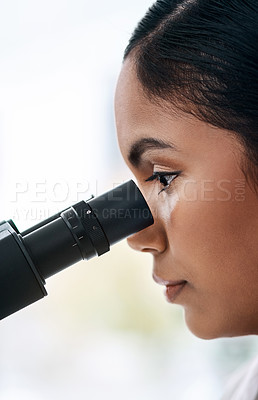 Buy stock photo Closeup shot of an attractive young female scientist looking through a microscope while working in a laboratory