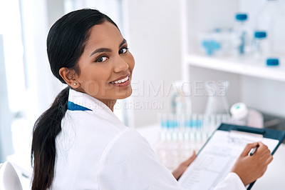 Buy stock photo Cropped portrait of an attractive young female scientist smiling while writing on a clipboard in a laboratory