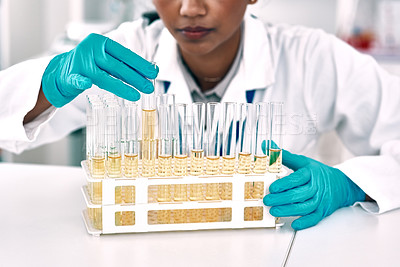Buy stock photo Cropped shot of an unrecognizable female scientist conducting an experiment with a tray of test tubes in a laboratory