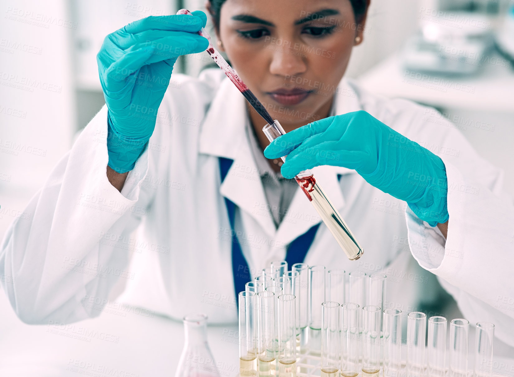 Buy stock photo Cropped shot of an attractive young female scientist transferring a blood sample from a pipette to a test tube in a laboratory