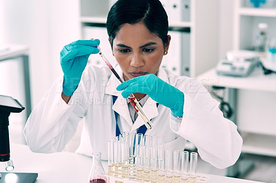 Buy stock photo Cropped shot of an attractive young female scientist transferring a blood sample from a pipette to a test tube in a laboratory