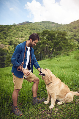 Buy stock photo Full length shot of a handsome young man standing with his golden retriever during a hike
