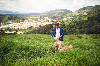 Buy stock photo Full length shot of a handsome young man walking with his golden retriever during a hike