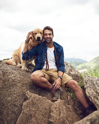Buy stock photo Cropped shot of a handsome young man sitting on a rock with his golden retriever after a day out hiking