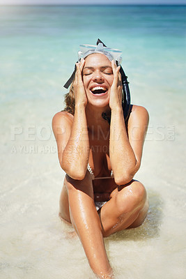 Buy stock photo Cropped shot of an attractive young woman in scuba gear laughing while sitting on the beach