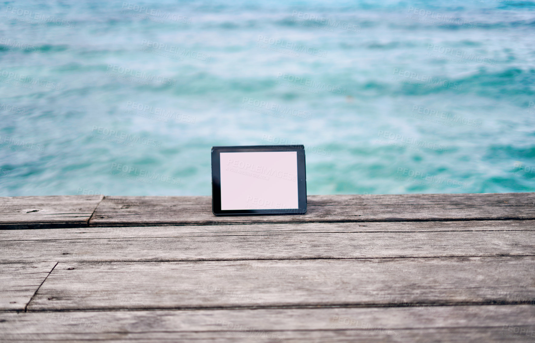 Buy stock photo Still life shot of a digital tablet placed on a boardwalk overlooking the ocean in Raja Ampat, Indonesia