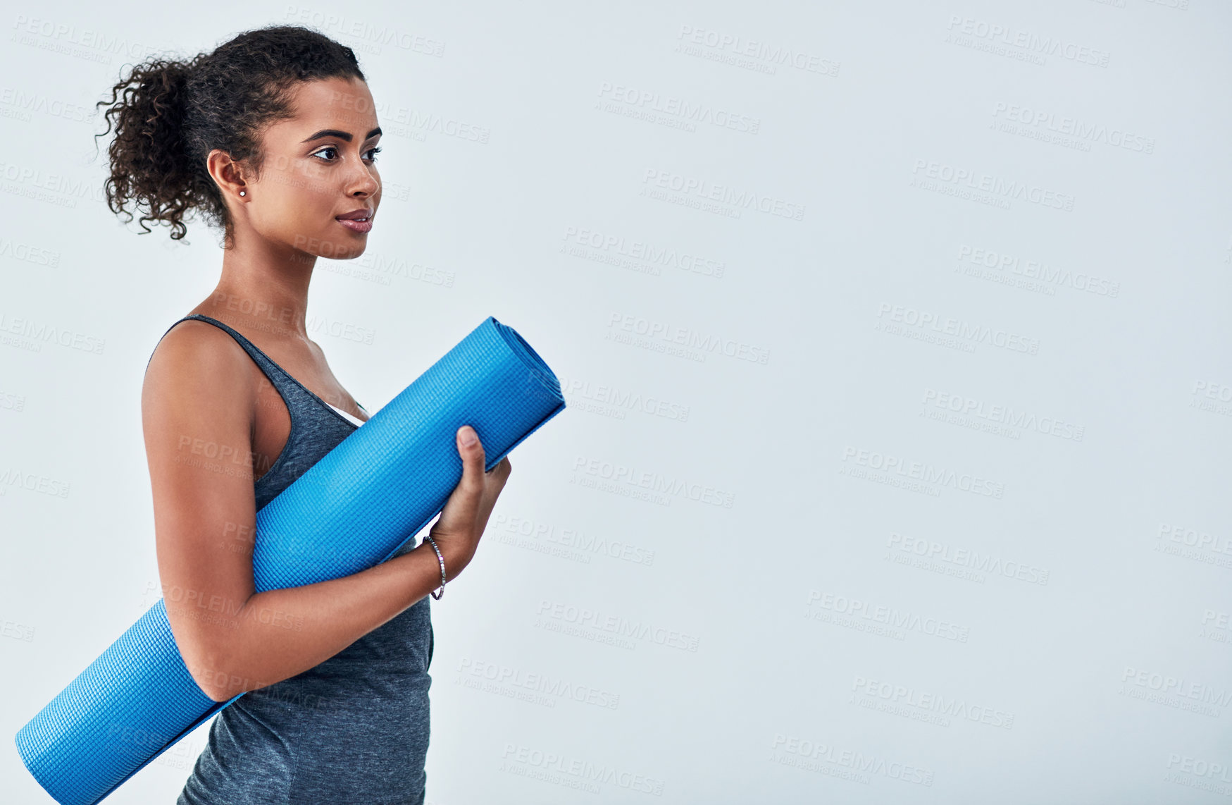Buy stock photo Cropped shot of an attractive young woman posing with her yoga mat against a grey background