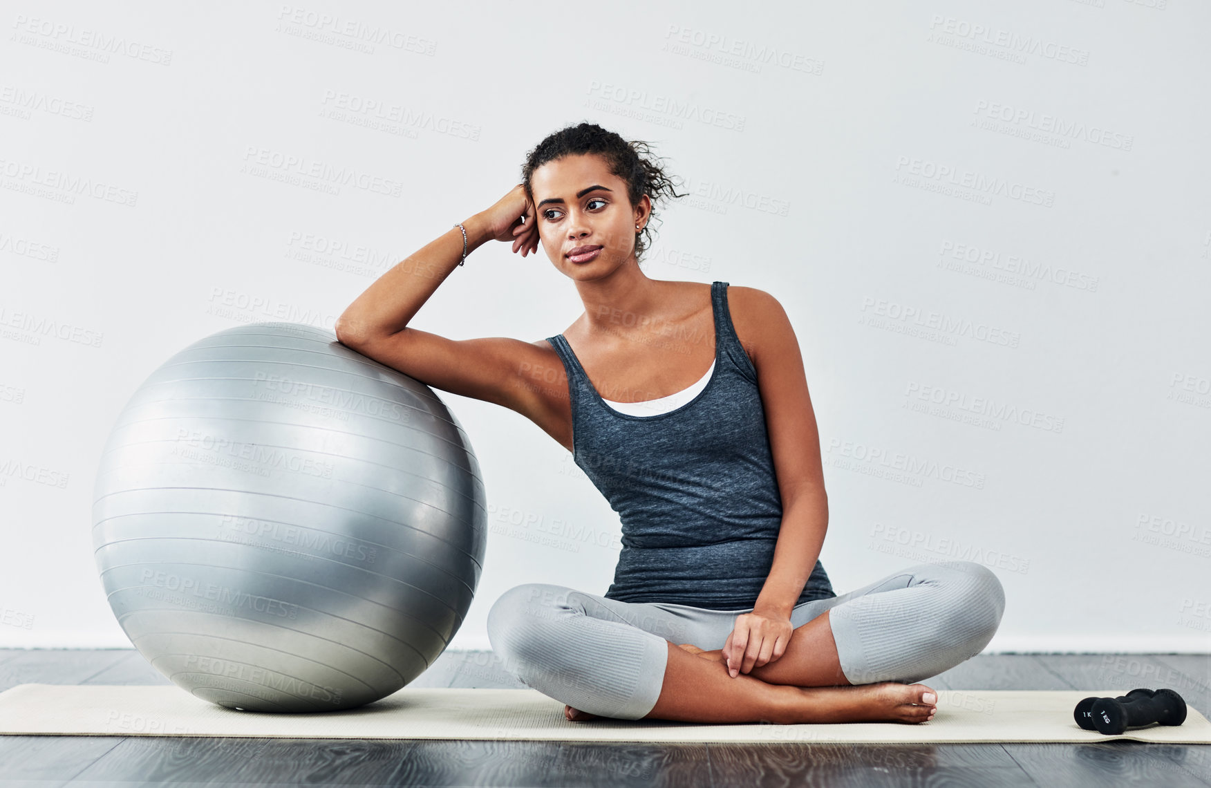 Buy stock photo Shot of a sporty young woman leaning against a exercise ball