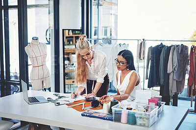 Buy stock photo Shot of two young fashion designers working together in a workshop