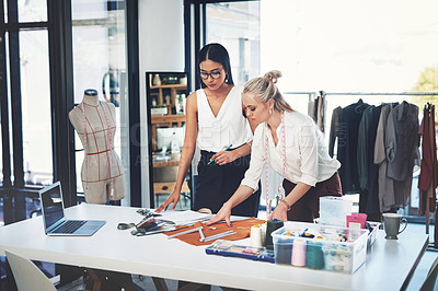 Buy stock photo Shot of two young fashion designers working together in a workshop