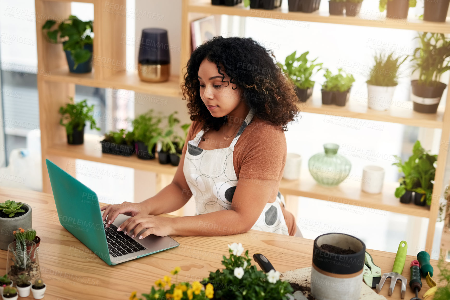 Buy stock photo High angle shot of an attractive young female botanist working on a laptop in her florist
