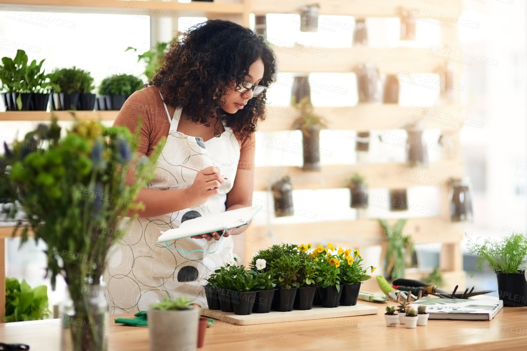 Buy stock photo Cropped shot of an attractive young female botanist making notes while working in her florist