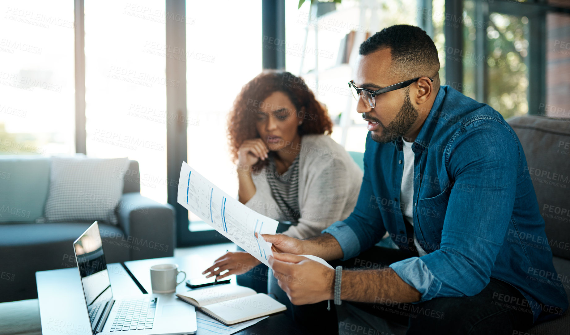 Buy stock photo Shot of a young couple planning their budget together at home